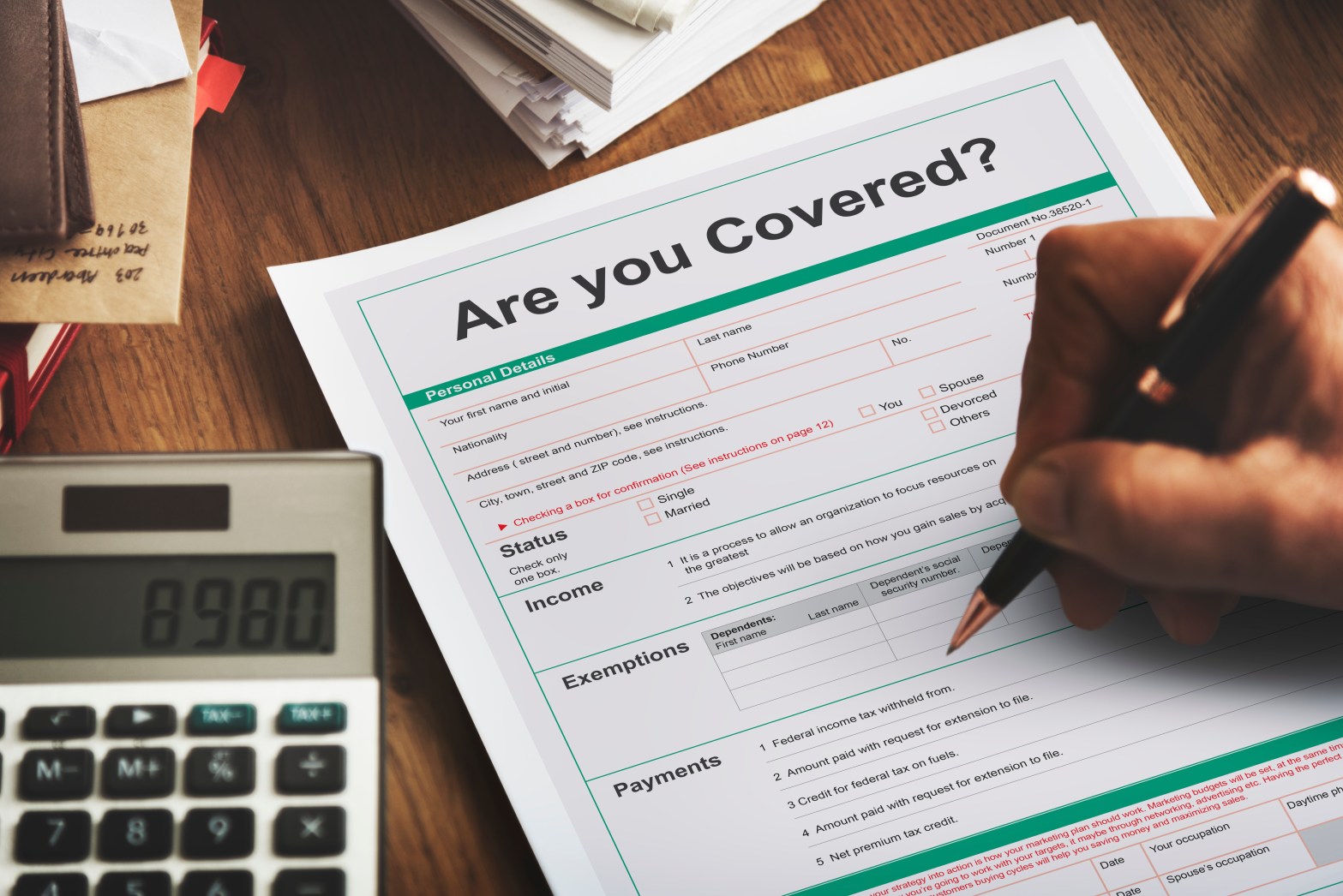 Close-up of a hand signing insurance paperwork which asks “Are You Covered?”