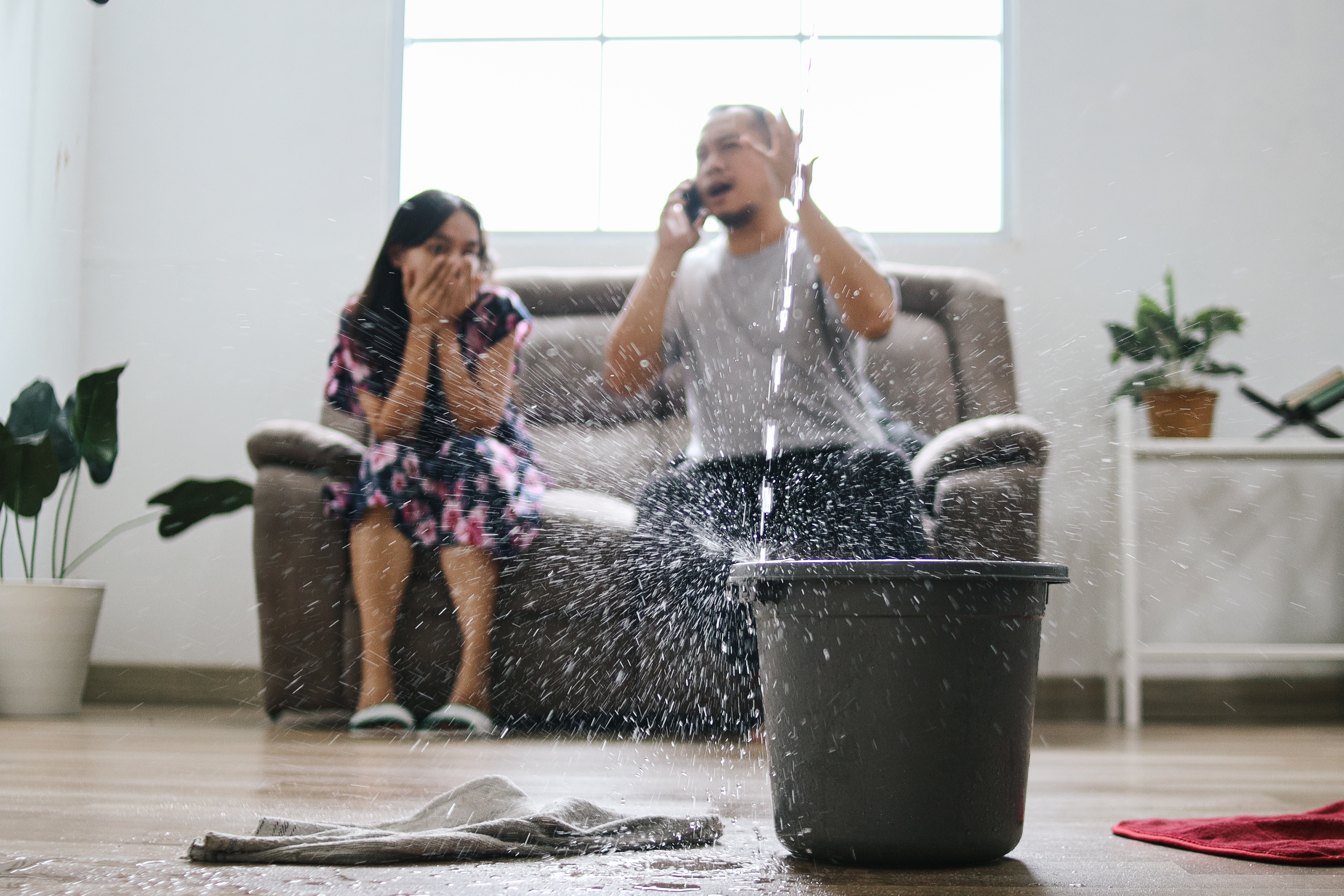 A homeowner with a leaky roof calls their insurance agency on the phone.