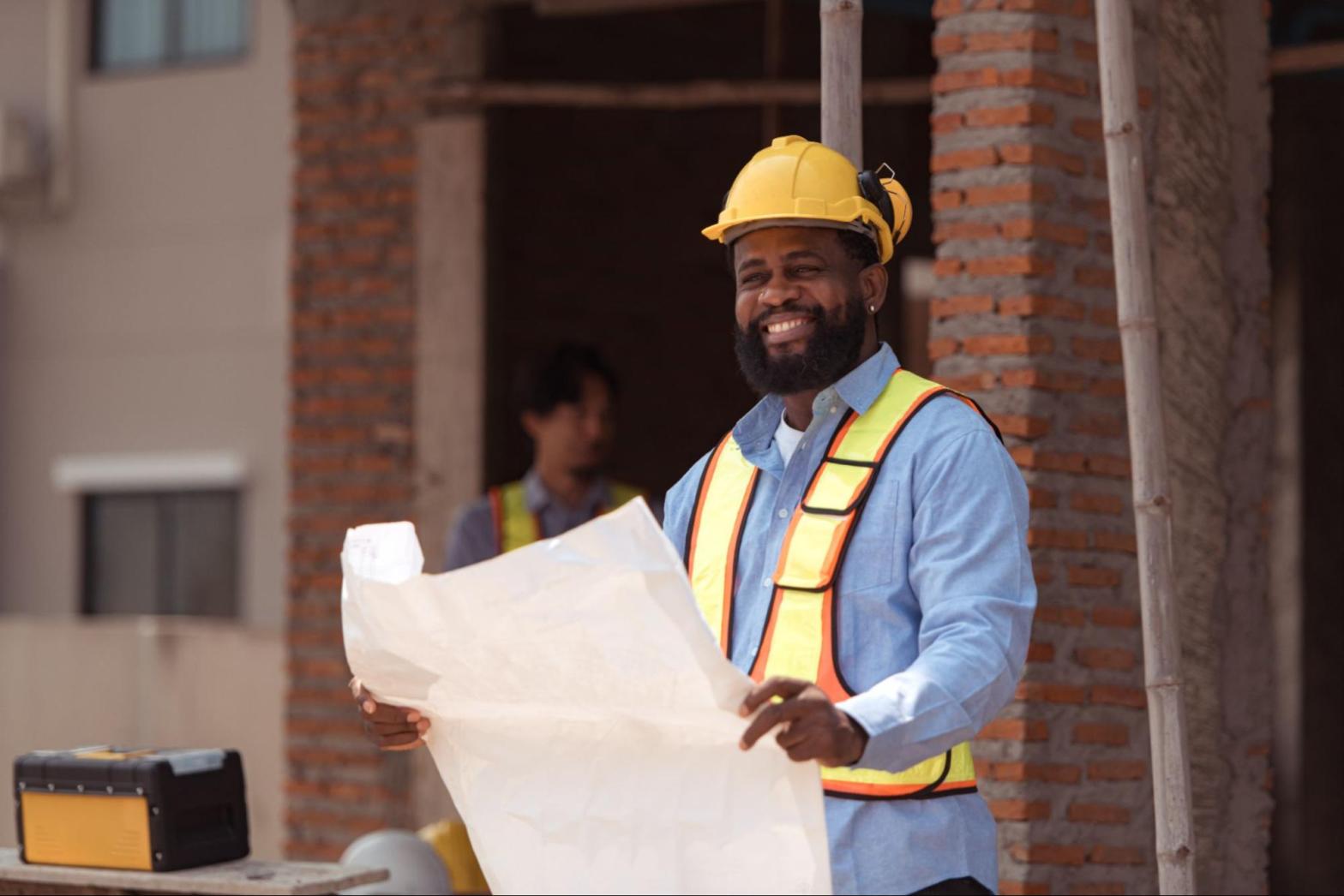 A contractor surveys the jobsite with plans in hand.