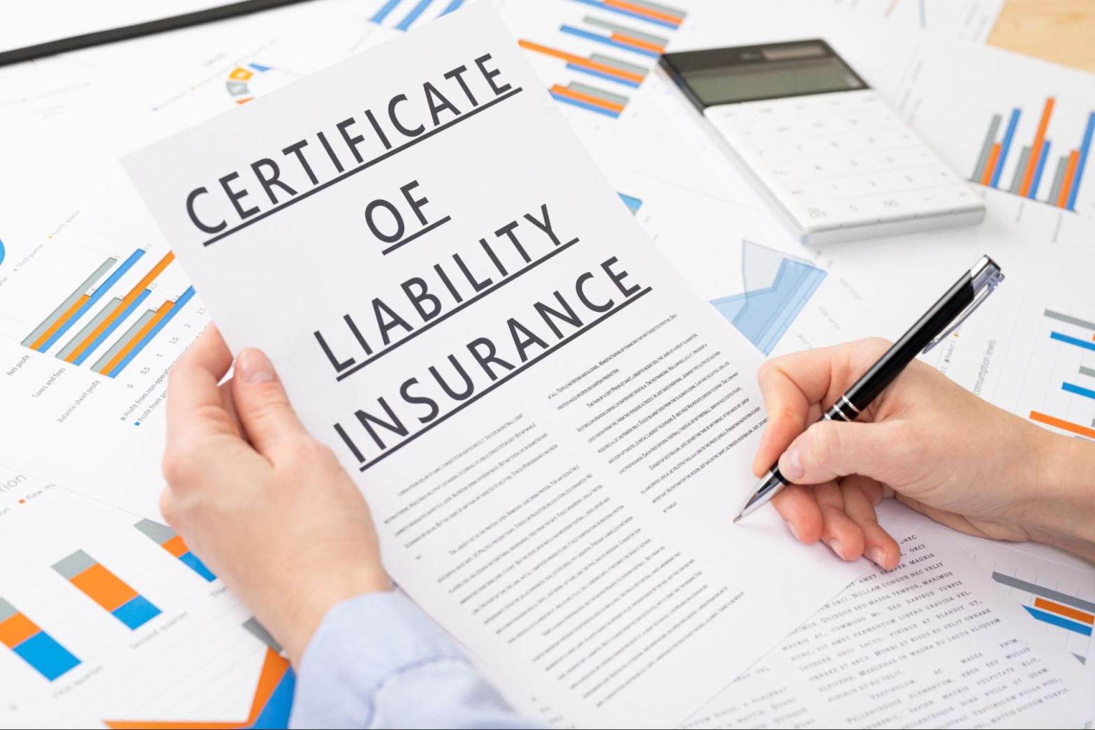 Closeup on a hand signing a certificate of liability insurance.