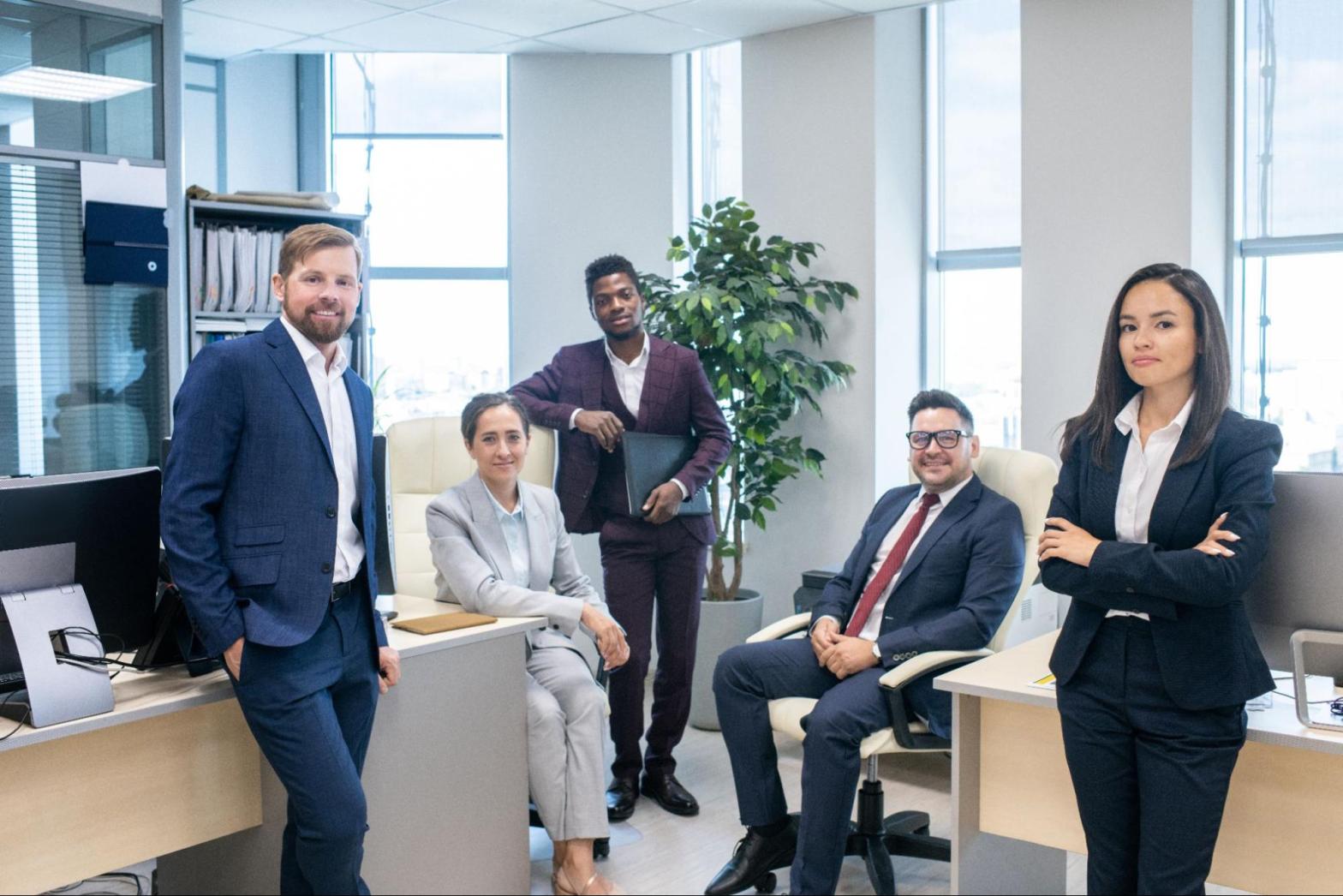 An insurance company poses for a group photo sitting and standing in an office.