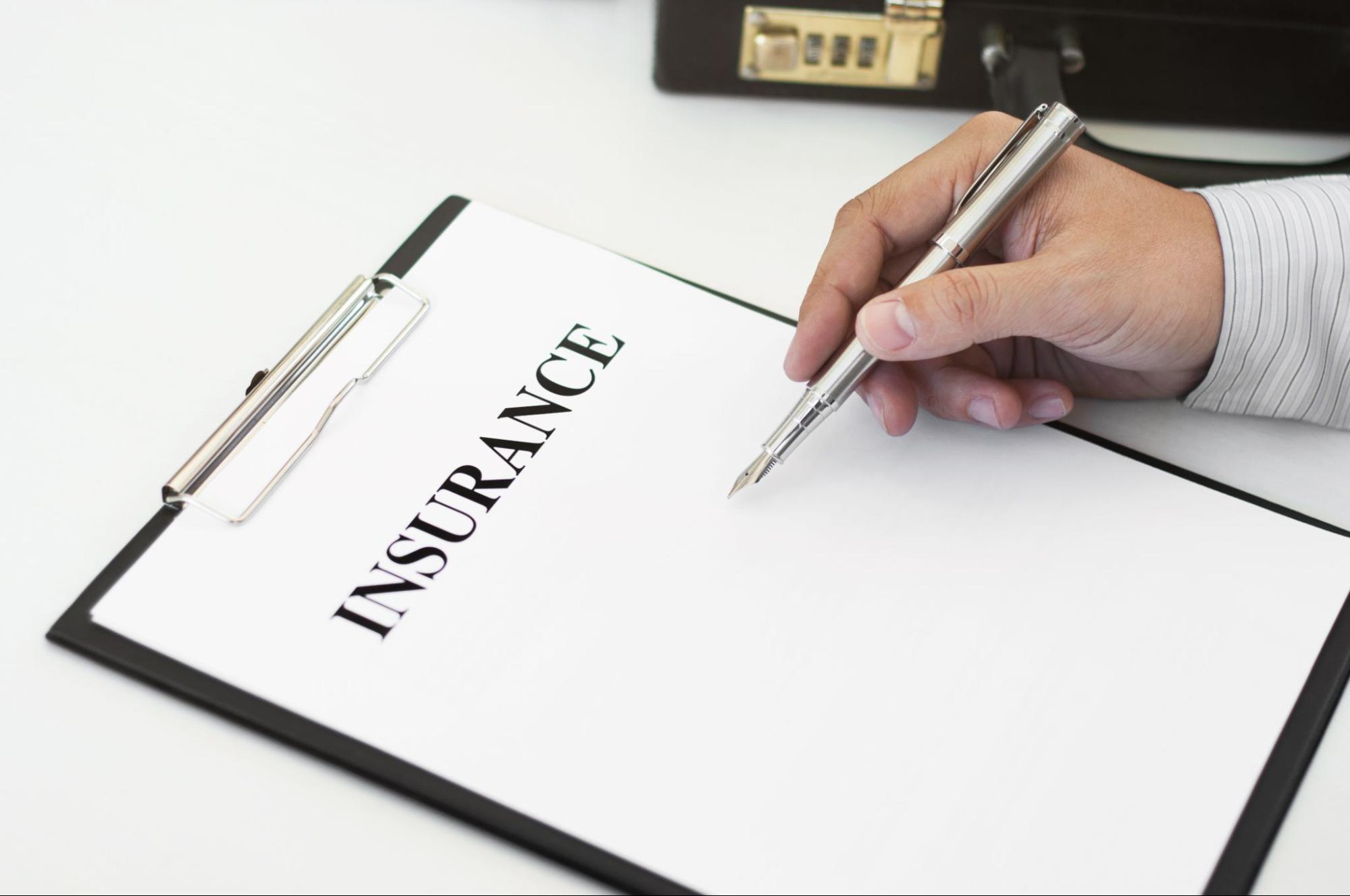 Insurance agent filling out a blank policy form, representing law and insurance consulting services