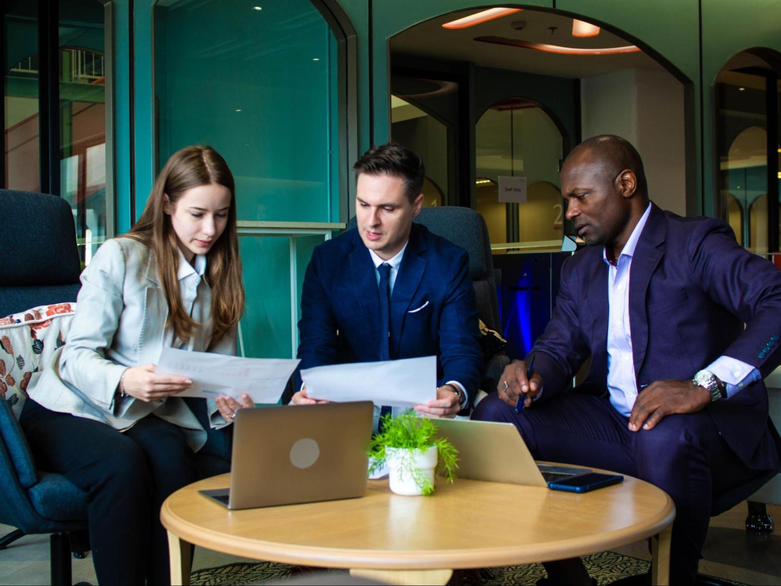 Three businesspeople discuss insurance policies in a work meeting.