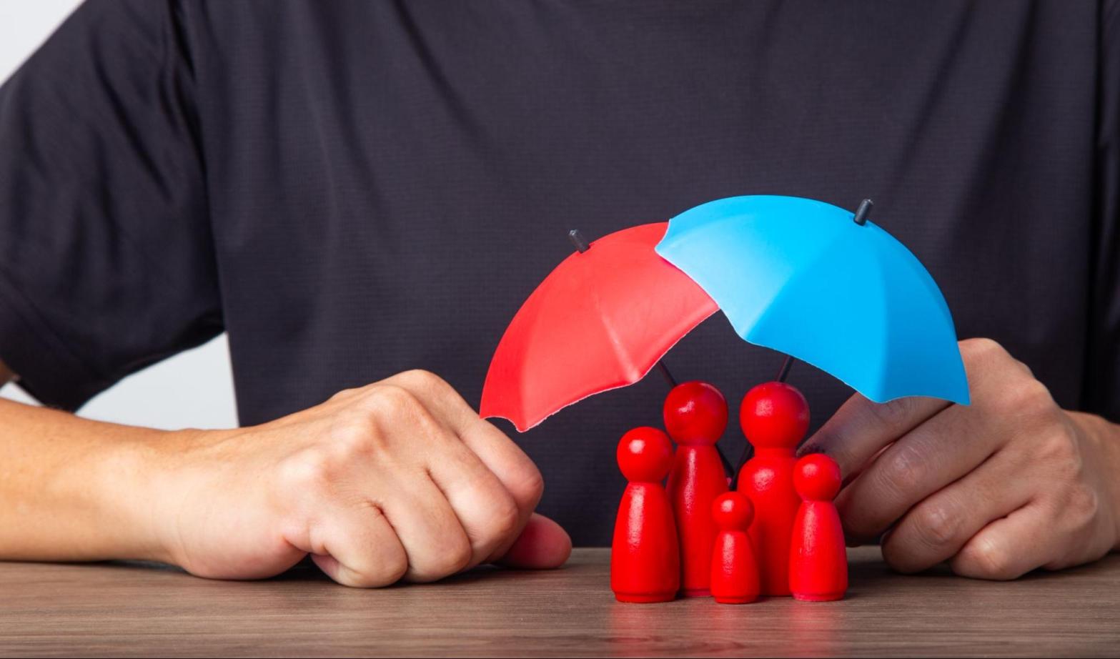A figurine model of a family covered by umbrellas to symbolize their insurance coverage.