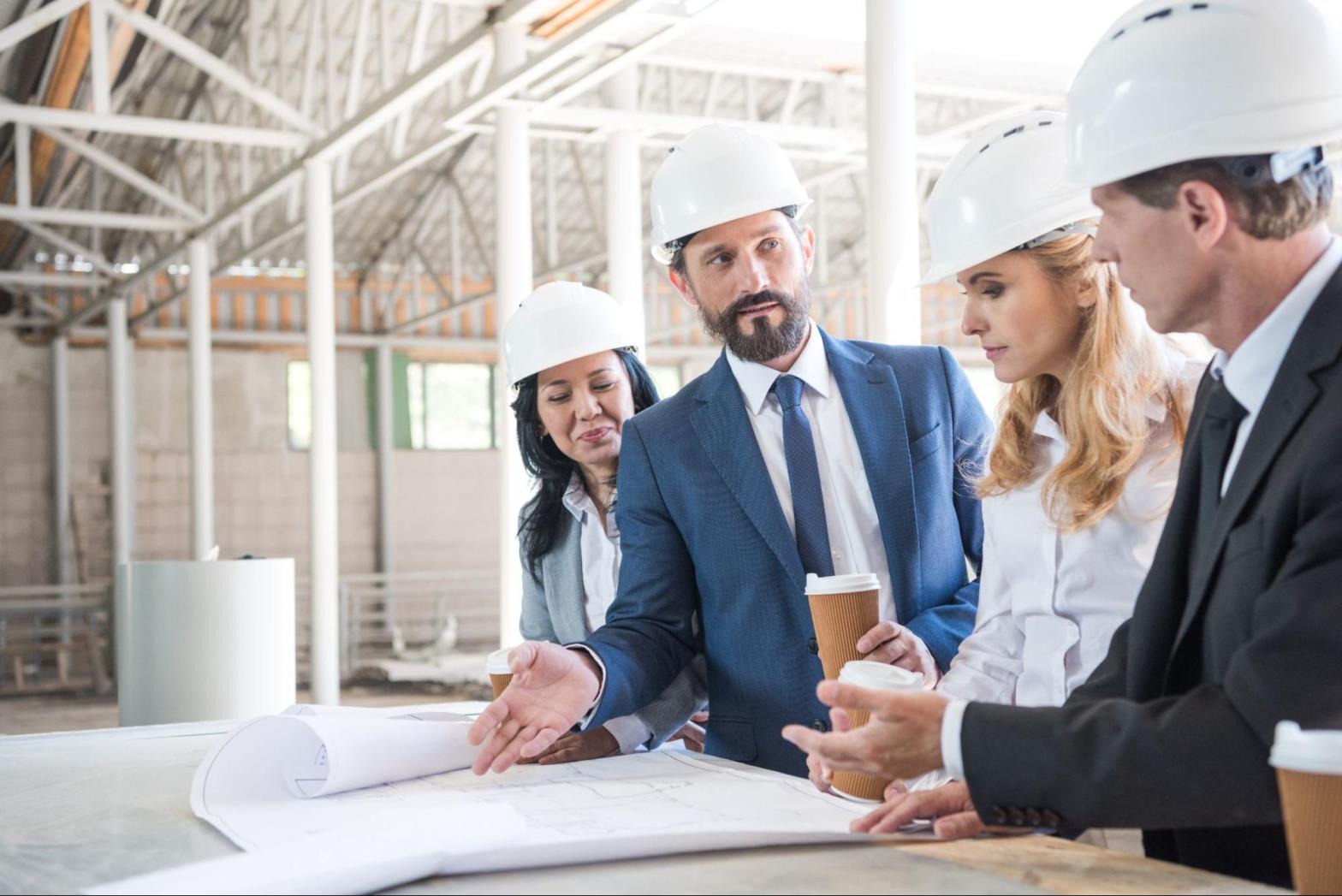 Contractors meeting with clients at a construction site to discuss project scope, responsibilities, and liability insurance
