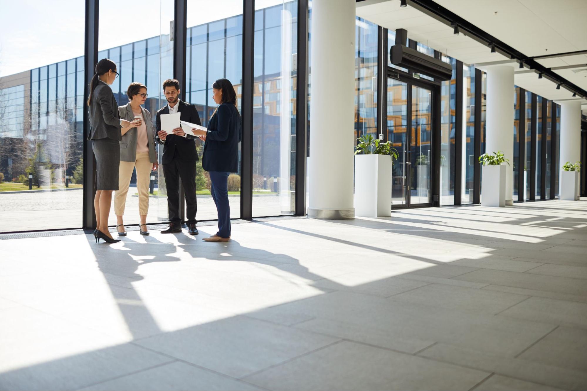 Business team analyzing property and insurance documents in a commercial building lobby