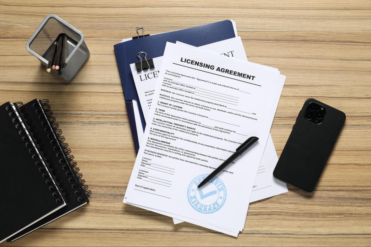 Licensing agreement documents and stationery on a wooden table during a surety bond review