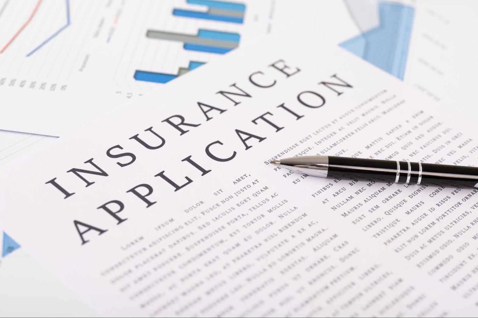 A black pen resting on insurance application literature