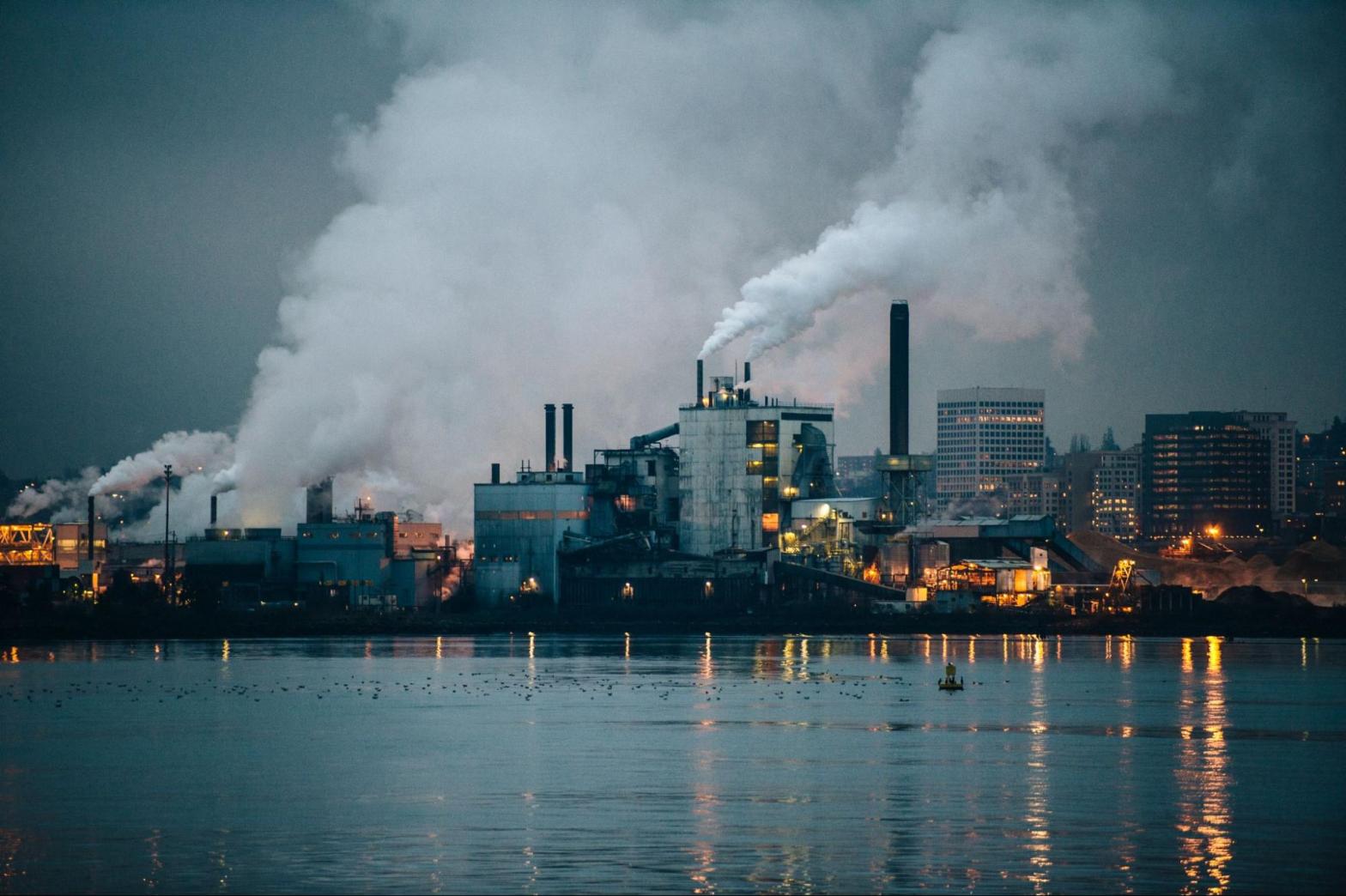 Industrial plant with illuminated smoke stacks releasing emissions at night