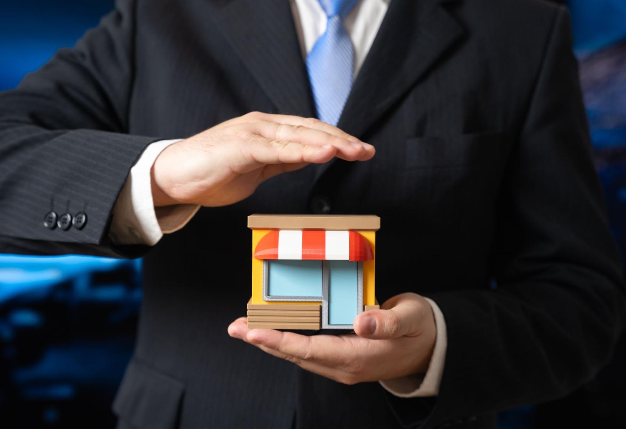 Business owner holding a small shop representing business owners' policy coverage that protects small businesses from property and liability risks.