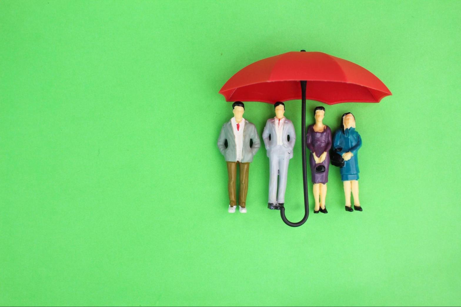 Toy umbrella over models of business professionals.