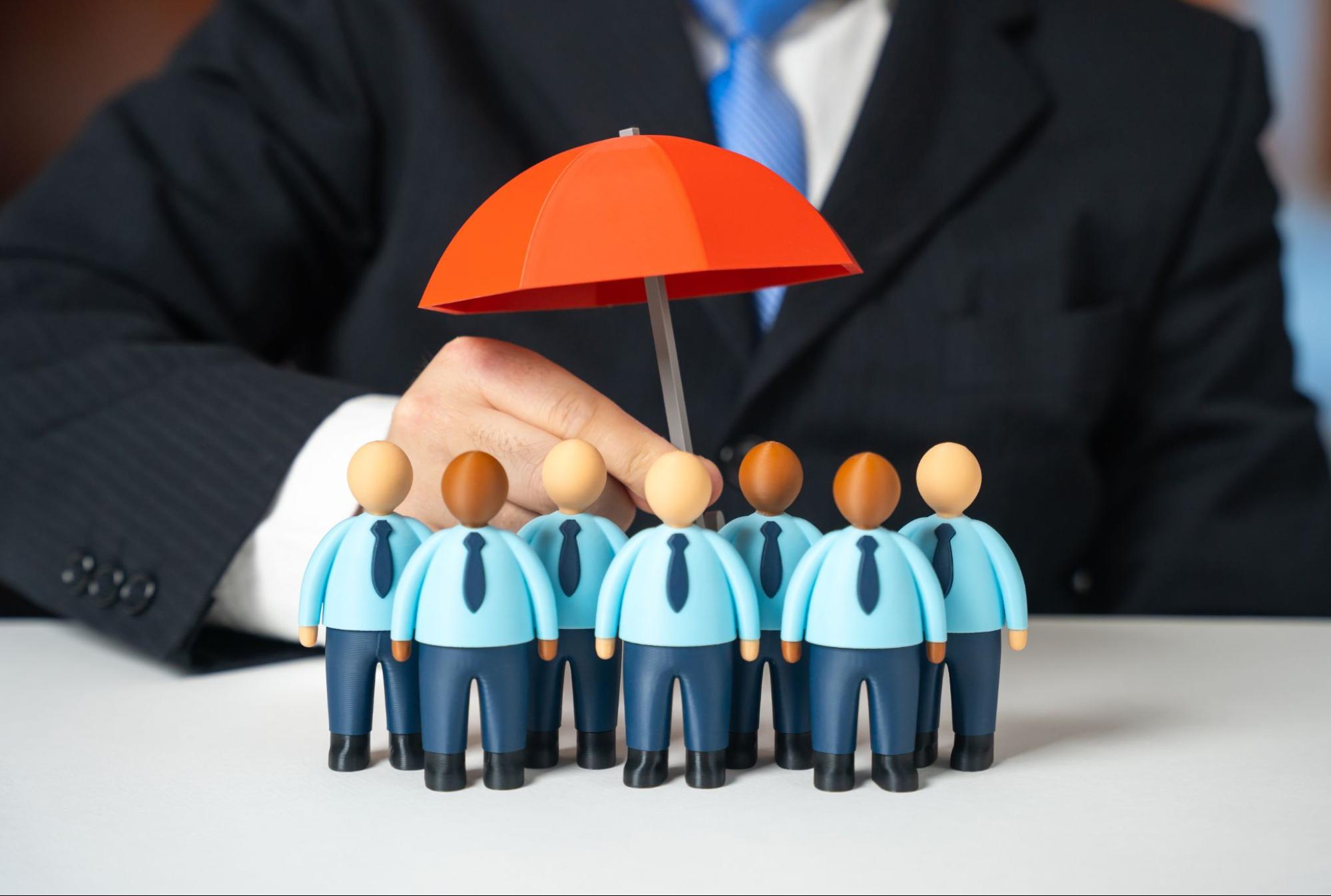 Figurines representing business leaders protected by an umbrella symbolizing management liability insurance coverage