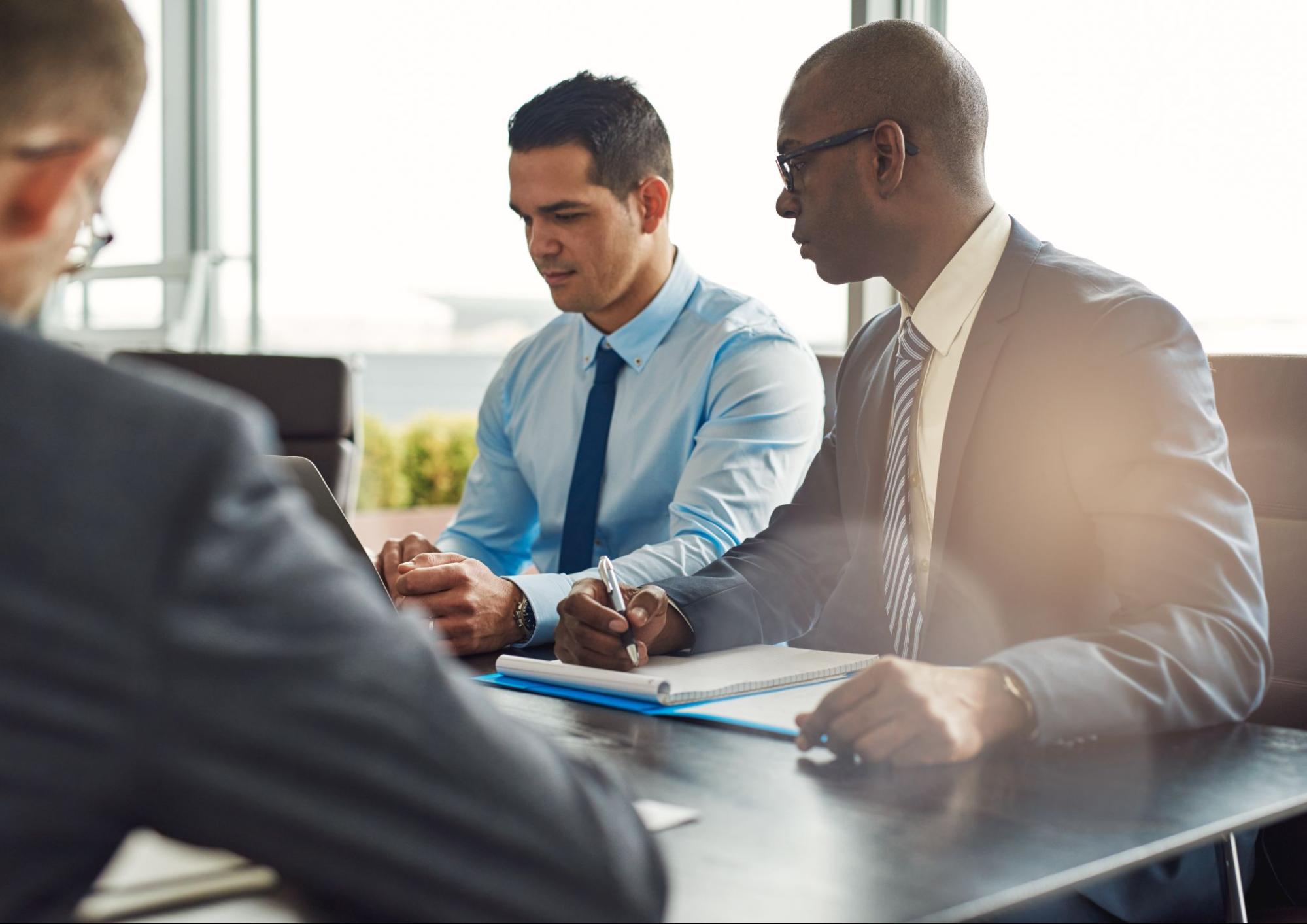 Insurance professional meeting with two business leaders to review management liability insurance coverage