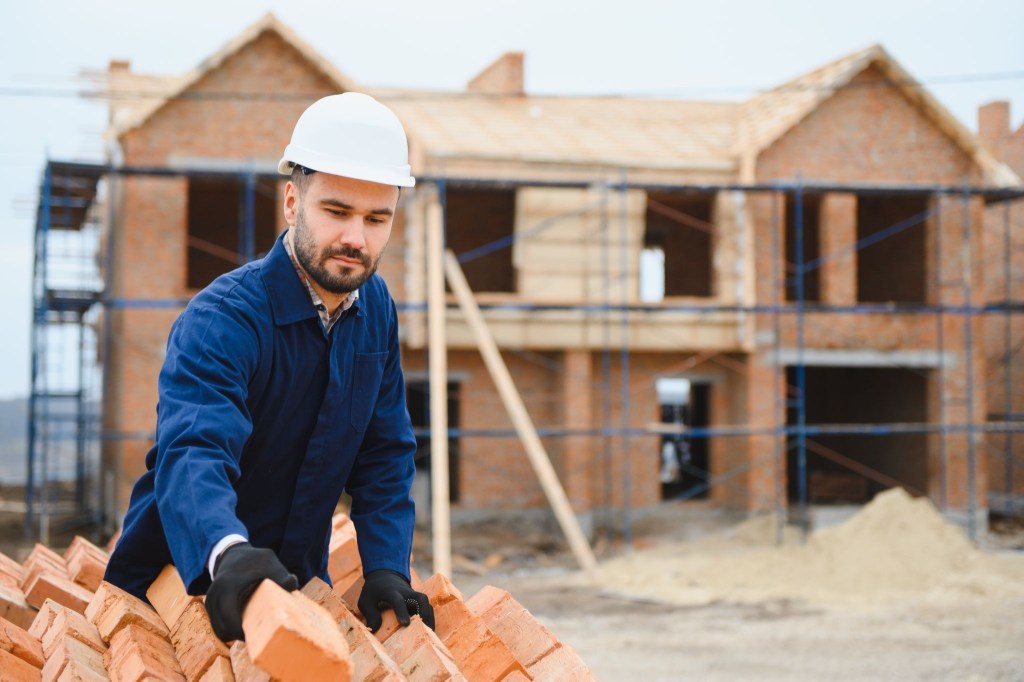 Construction worker in protective gear inspecting a building project with builder's risk insurance coverage