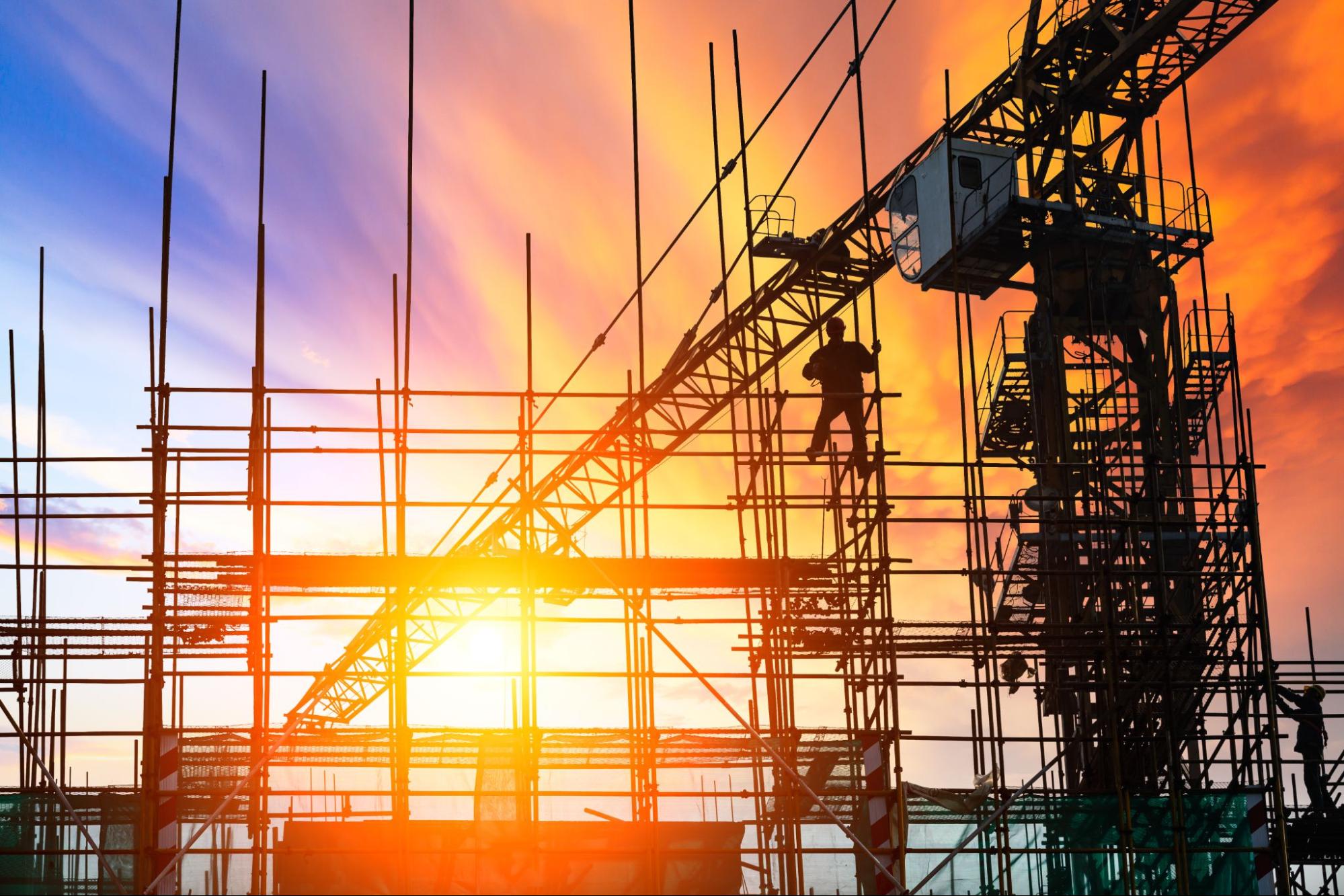 Worker climbing a structural steel frame at a construction site covered by builders risk insurance
