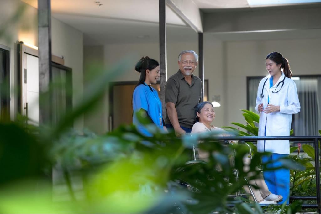 Senior couple consulting with healthcare professionals in a sunny senior living facility garden
